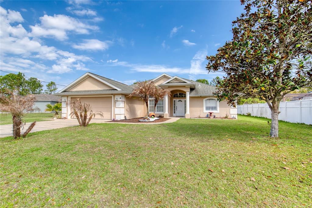 A single-story tan house with a two-car garage and a large front yard — 89 FELWOOD LANE, PALM COAST, FL