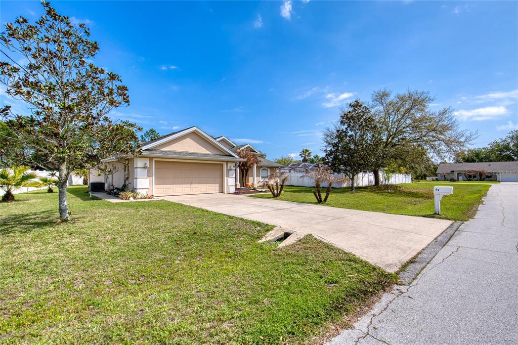 A single-story house with a beige exterior, a two-car garage, and a concrete driveway — 89 FELWOOD LANE, PALM COAST, FL