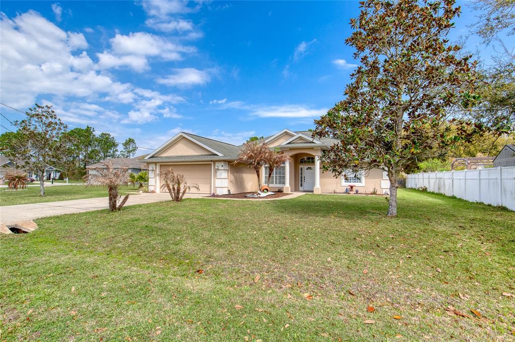 A single-story suburban house with a tan exterior, a two-car garage, and a front lawn — 89 FELWOOD LANE, PALM COAST, FL