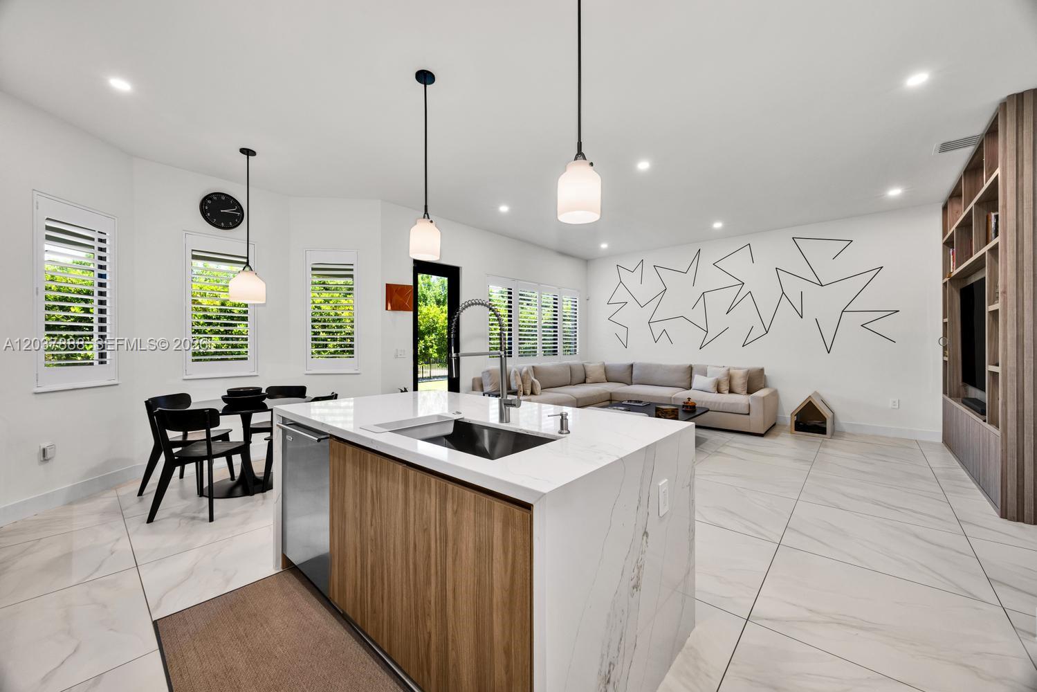 A modern open-concept kitchen and living area features a marble island and geometric wall art — 12021 SW 82nd Pl, Miami FL 33156, MIAMI, FL