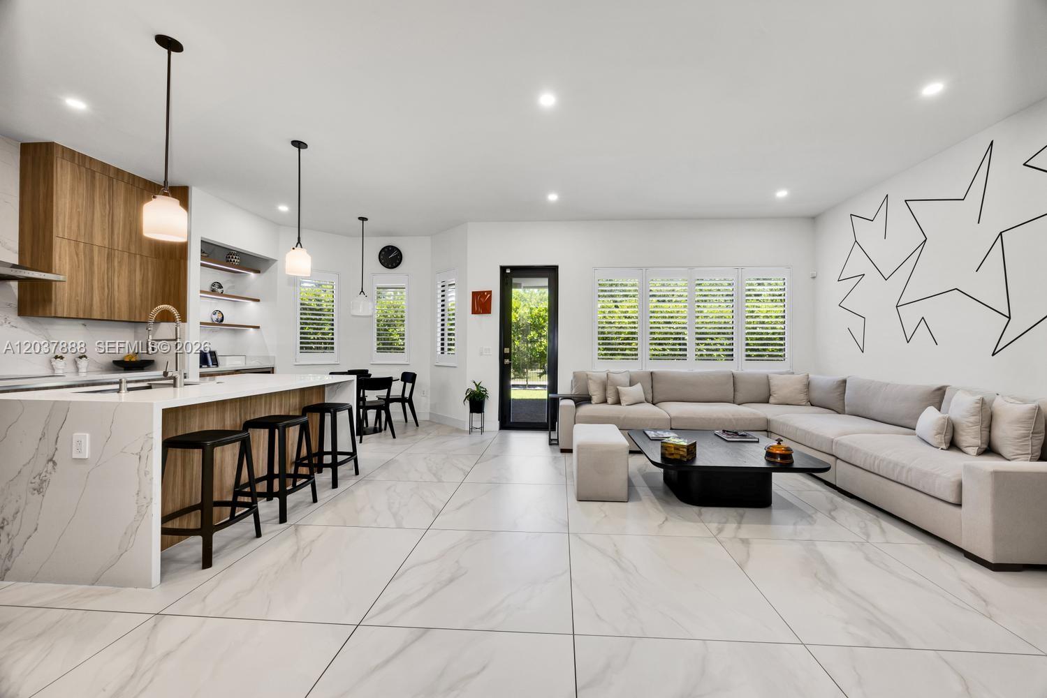 A modern open-concept kitchen and living area features white marble floors and a sectional sofa — 12021 SW 82nd Pl, Miami FL 33156, MIAMI, FL