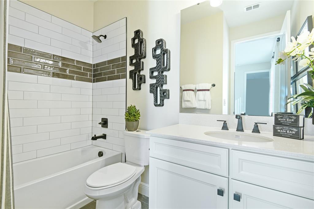 A bathroom features a white vanity, a toilet, and a shower-tub combo with tiled walls — 6410 CLOVER STREET, LAKE HAMILTON, FL