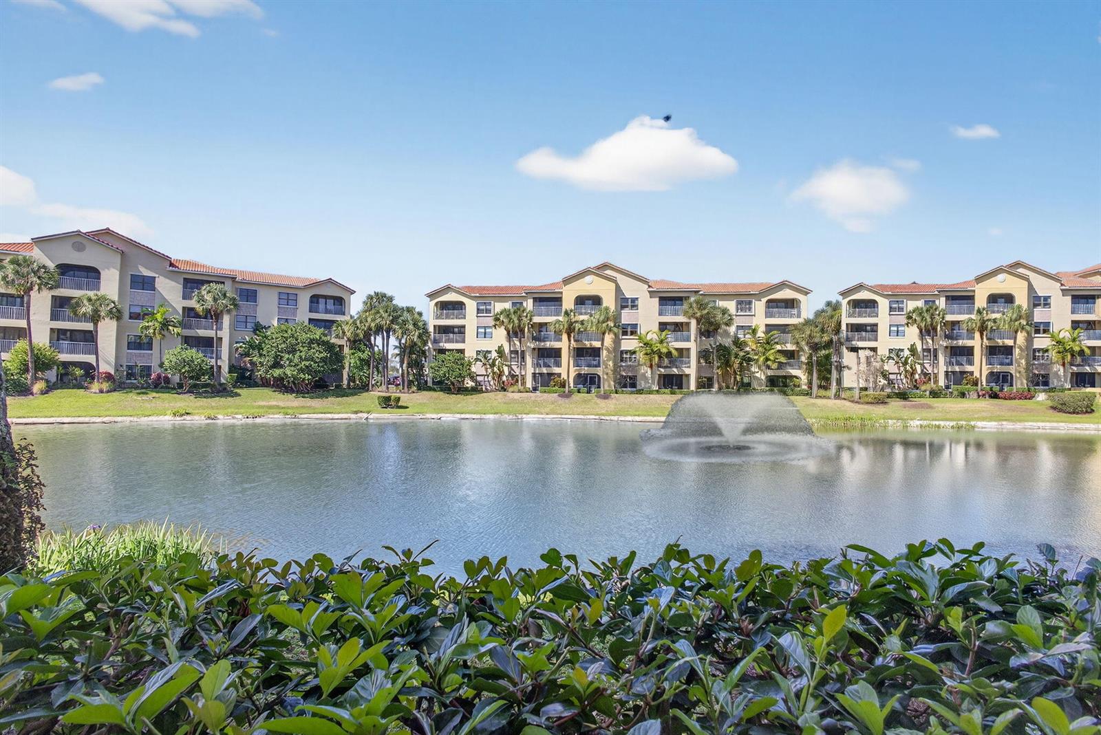 A pond with a fountain sits in front of three multi-story apartment buildings — 400 Uno Lago Drive # 103, Juno Beach FL 33408, JUNO BEACH, FL