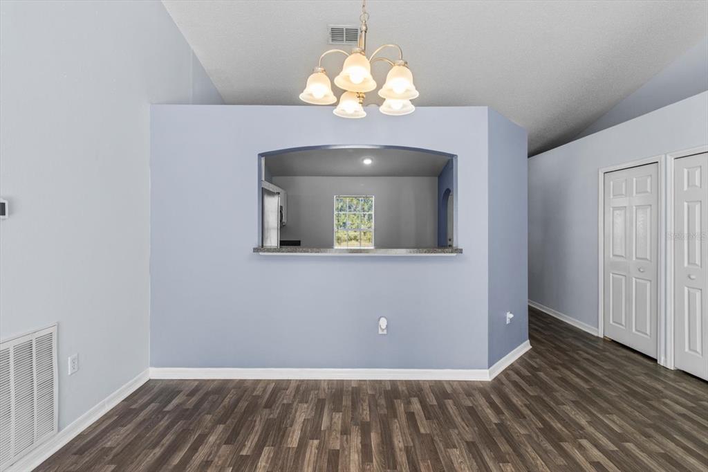 A dining area with wood-look flooring, a light blue wall, and a kitchen pass-through window — 7895 N SARAZEN DRIVE, CITRUS SPRINGS, FL
