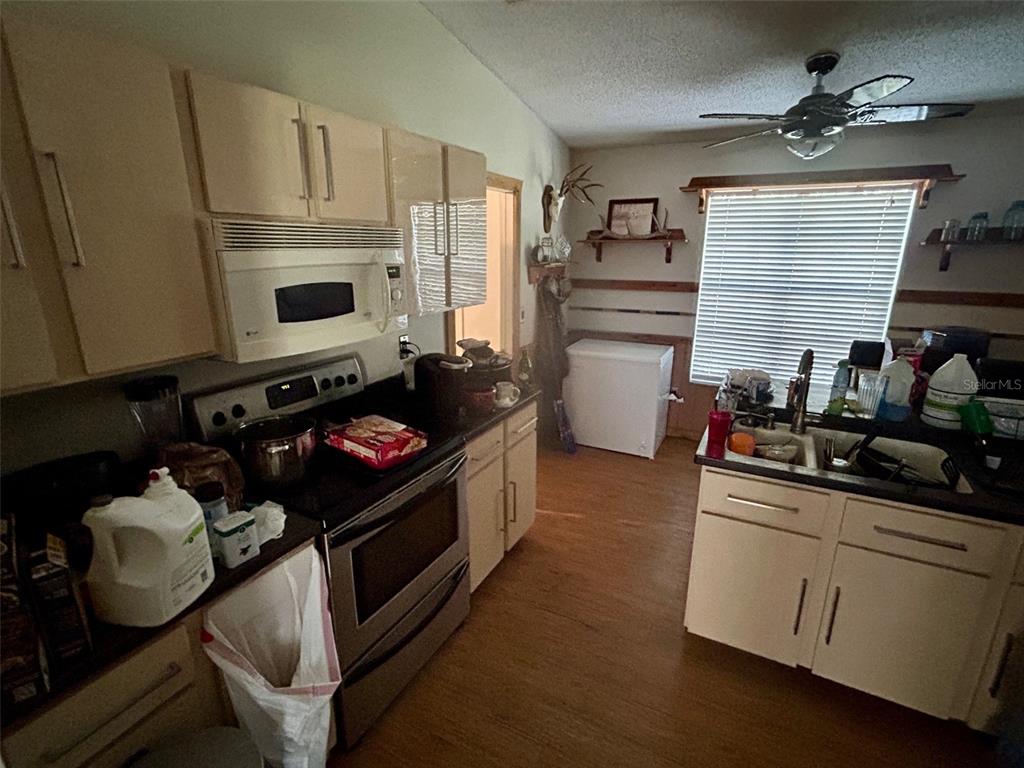 A kitchen features light-colored cabinetry, stainless steel appliances, a ceiling fan, and a chest freezer — 2293 BELEN DRIVE, DELTONA, FL
