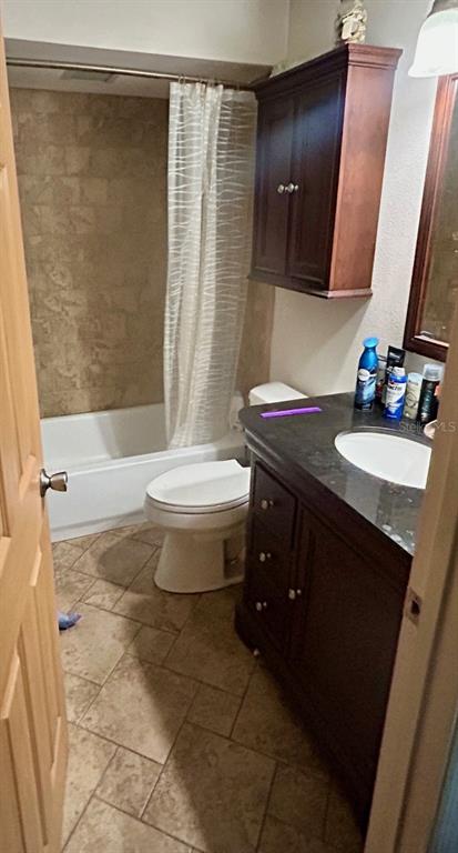 A bathroom features a dark wood vanity, a toilet, and a shower-tub combo with tiled walls — 2293 BELEN DRIVE, DELTONA, FL