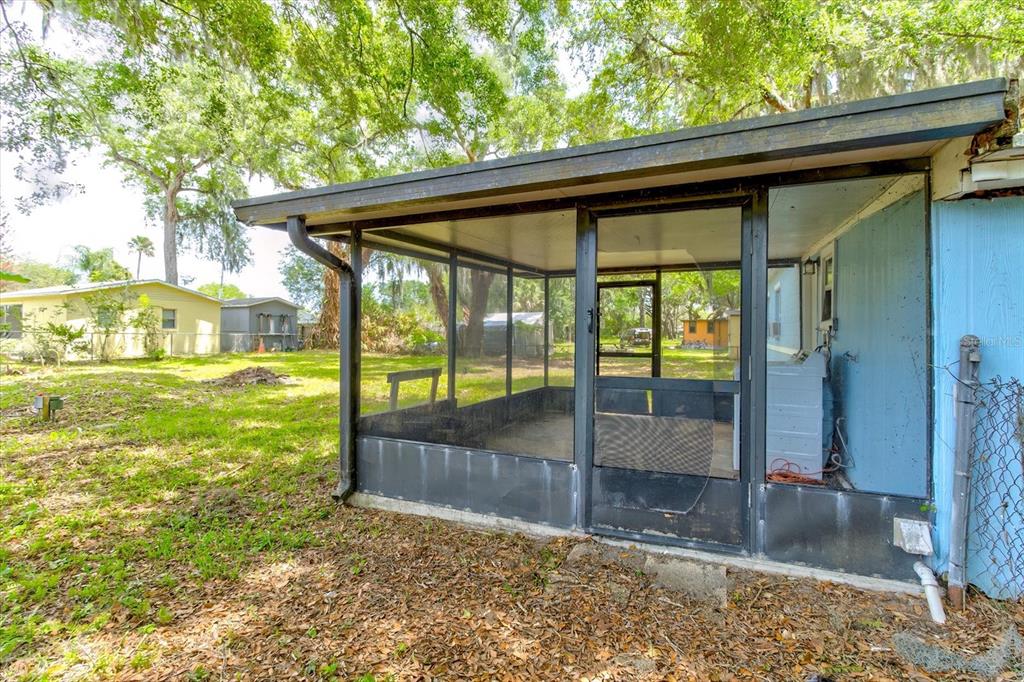 A screened-in porch with a concrete floor sits attached to the side of a house — 113 FRAN DRIVE, NEW SMYRNA BEACH, FL