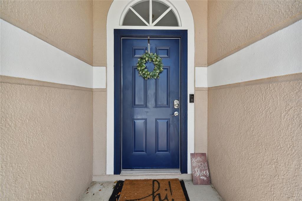 A blue front door with a wreath and a welcome mat sits under an arched transom — 24541 LAUREL RIDGE DRIVE, LUTZ, FL