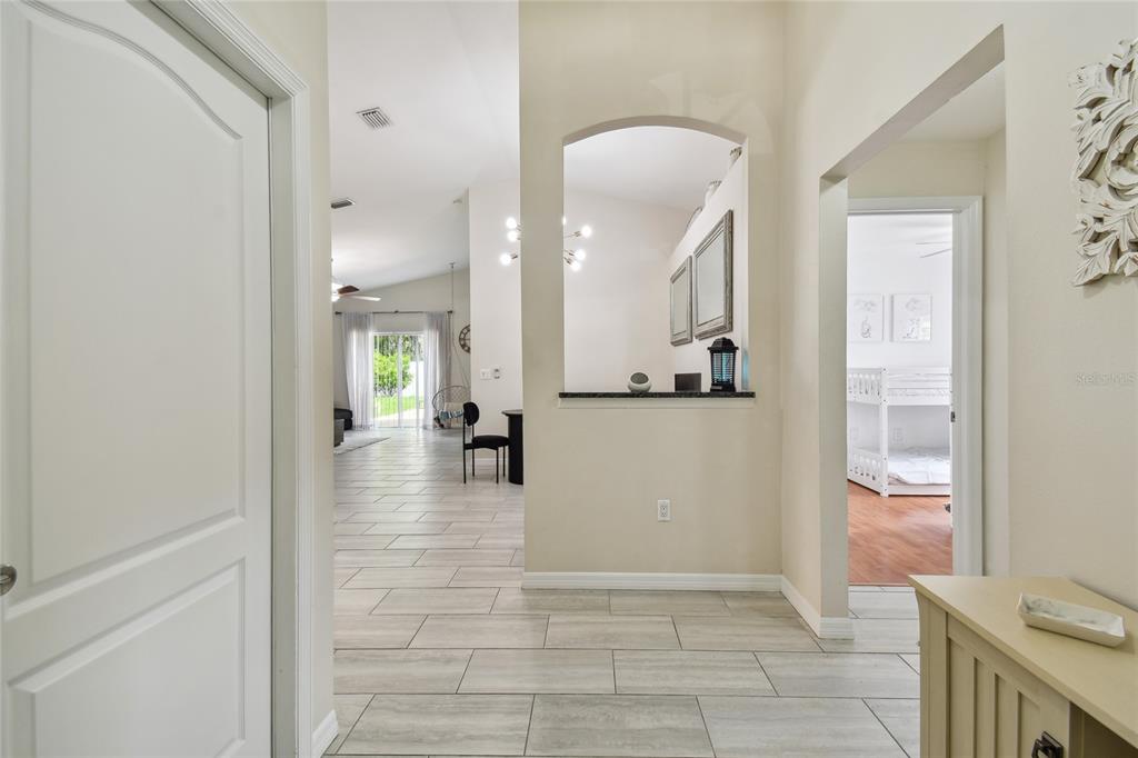 A bright entryway with tile flooring leads to an open living area and a bedroom — 24541 LAUREL RIDGE DRIVE, LUTZ, FL