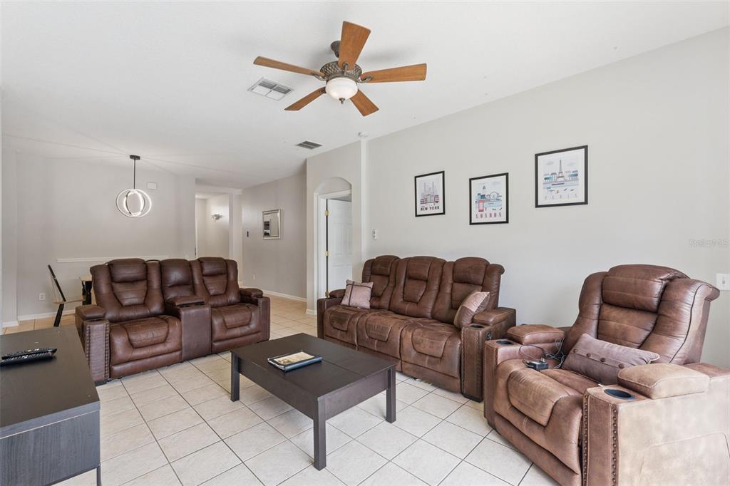 A living room features brown leather reclining furniture, a coffee table, and tile flooring — 8152 SUN PALM DRIVE, KISSIMMEE, FL