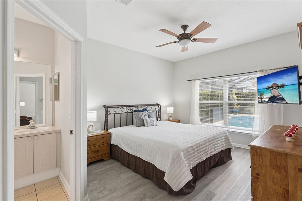 A bedroom with a metal bed frame, wood furniture, ceiling fan, and a pool view — 8152 SUN PALM DRIVE, KISSIMMEE, FL