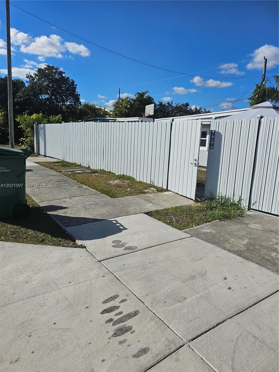 A white metal privacy fence encloses a property with a visible house number — 528 NW 10th St, Florida City FL 33034, FLORIDA CITY, FL