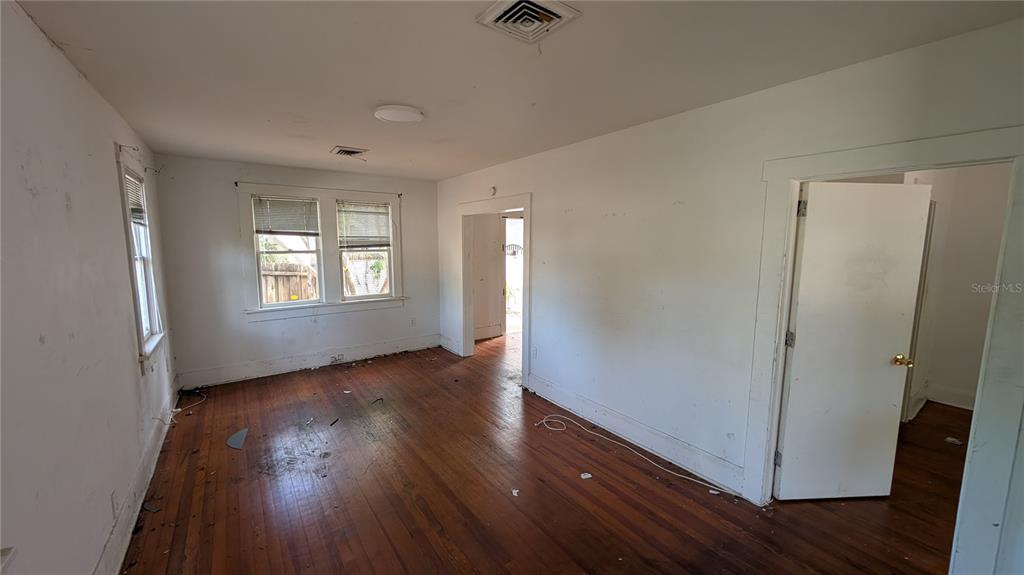 An empty room with white walls, hardwood floors, and two doorways leading to other rooms — 114 S BUNGALOW PARK AVENUE, TAMPA, FL