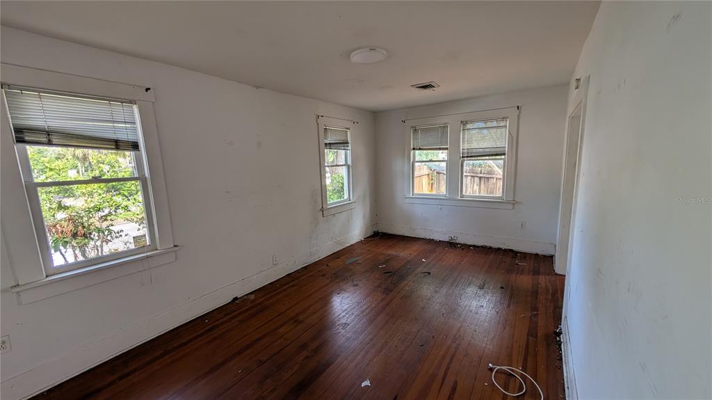 An empty room with white walls, hardwood floors, and three windows with blinds — 114 S BUNGALOW PARK AVENUE, TAMPA, FL