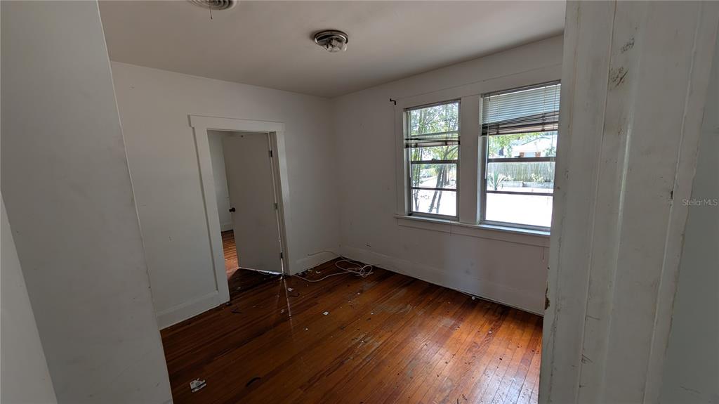 An empty bedroom features white walls, hardwood floors, and two windows with blinds — 114 S BUNGALOW PARK AVENUE, TAMPA, FL