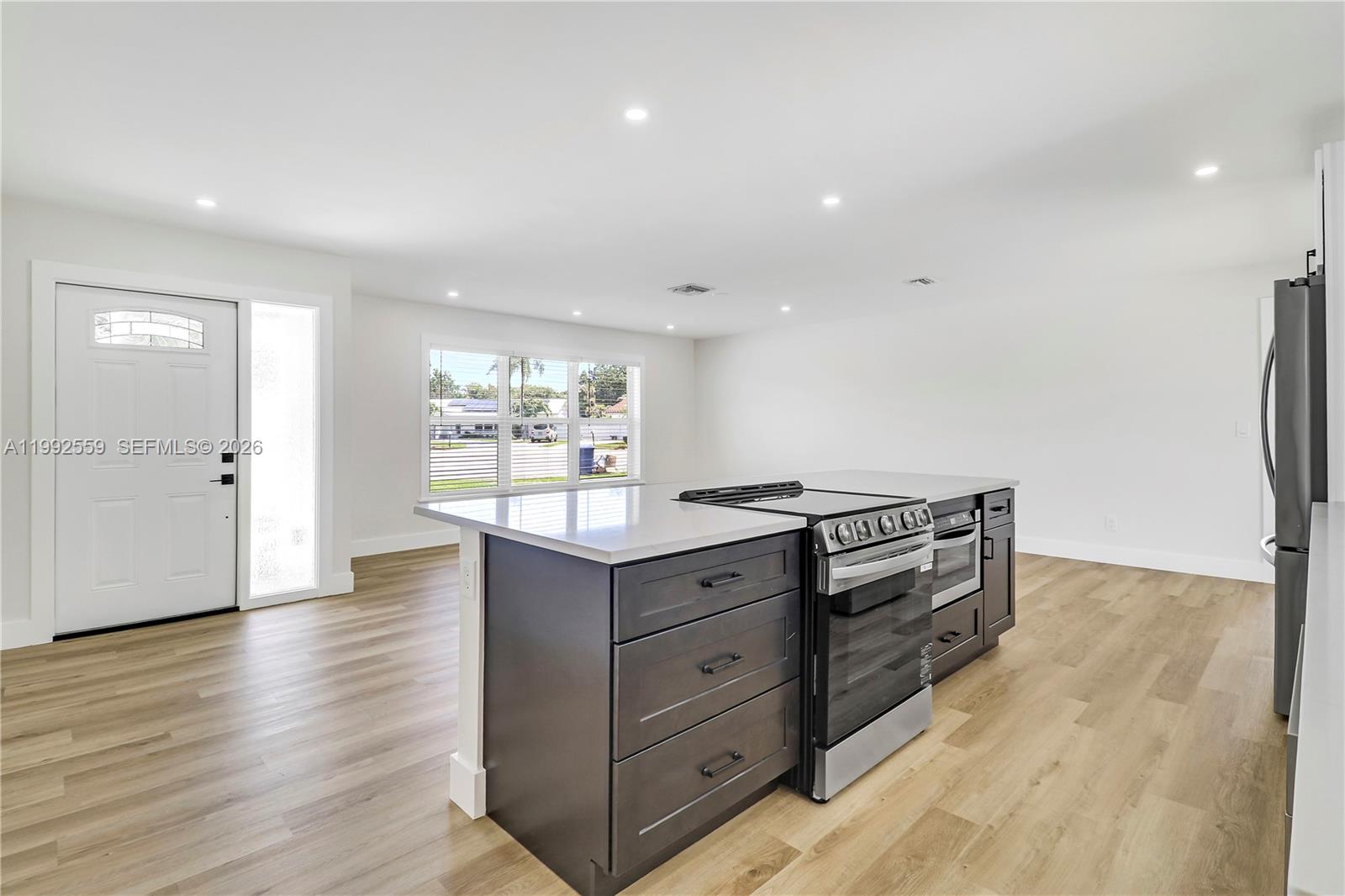 A kitchen island with a built-in stove sits on light wood flooring in a room — 404 Highwood Circle, Jupiter FL 33458, JUPITER, FL