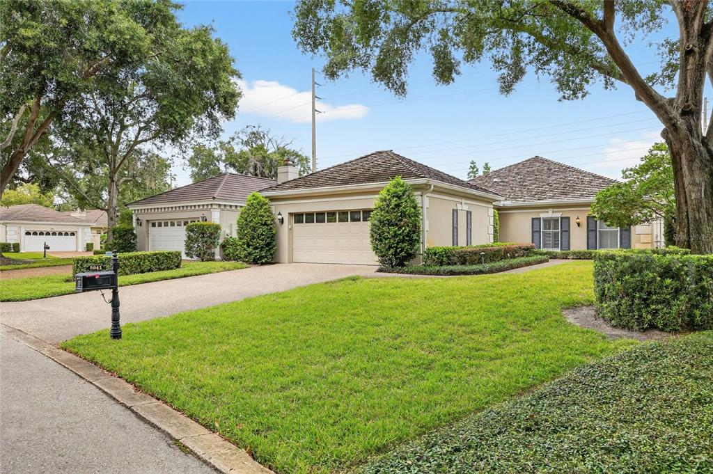 A single-story house with a beige stucco exterior, a multi-car garage, and a manicured lawn — 5941 CHESAPEAKE PARK UNIT GE, ORLANDO, FL