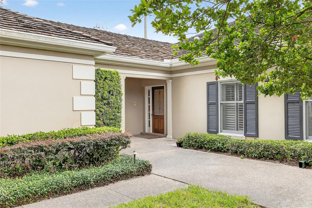 The exterior of a house features a concrete walkway leading to a wooden front door — 5941 CHESAPEAKE PARK UNIT GE, ORLANDO, FL
