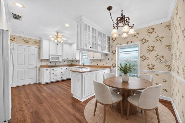 A kitchen and dining area with white cabinets, floral wallpaper, and a round wooden table — 5941 CHESAPEAKE PARK UNIT GE, ORLANDO, FL