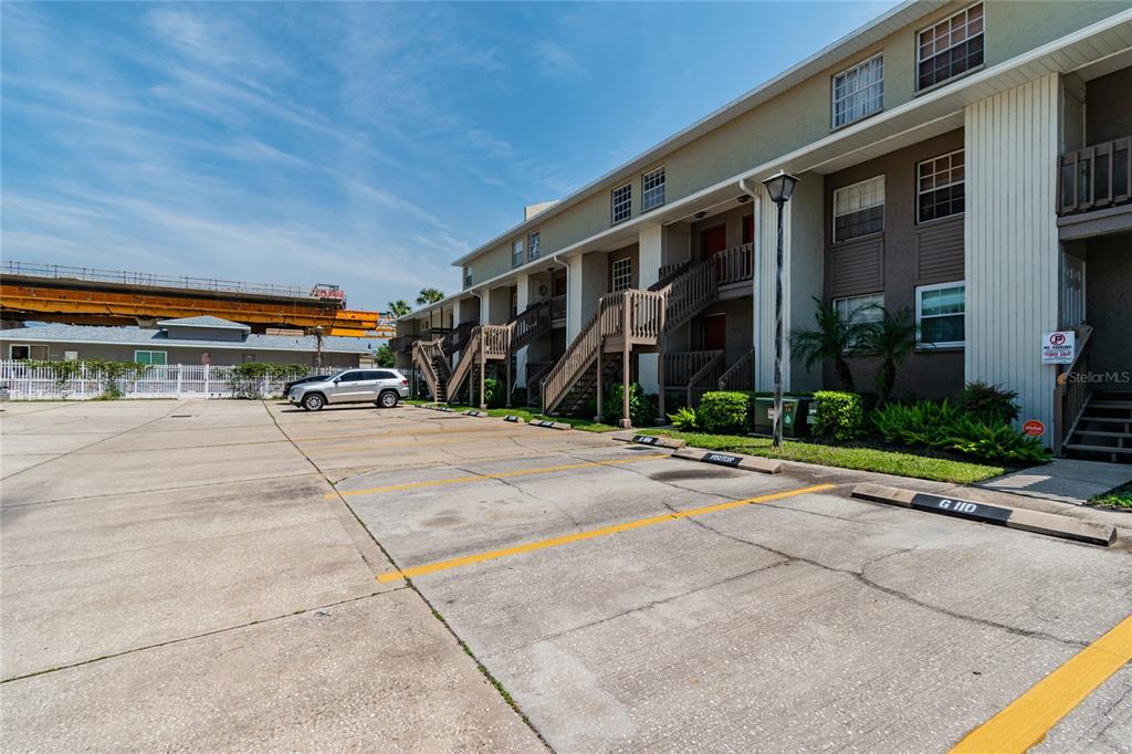 An exterior view of a multi-story apartment building with a paved parking lot in front — 4875 W MCELROY AVENUE UNIT G208, TAMPA, FL