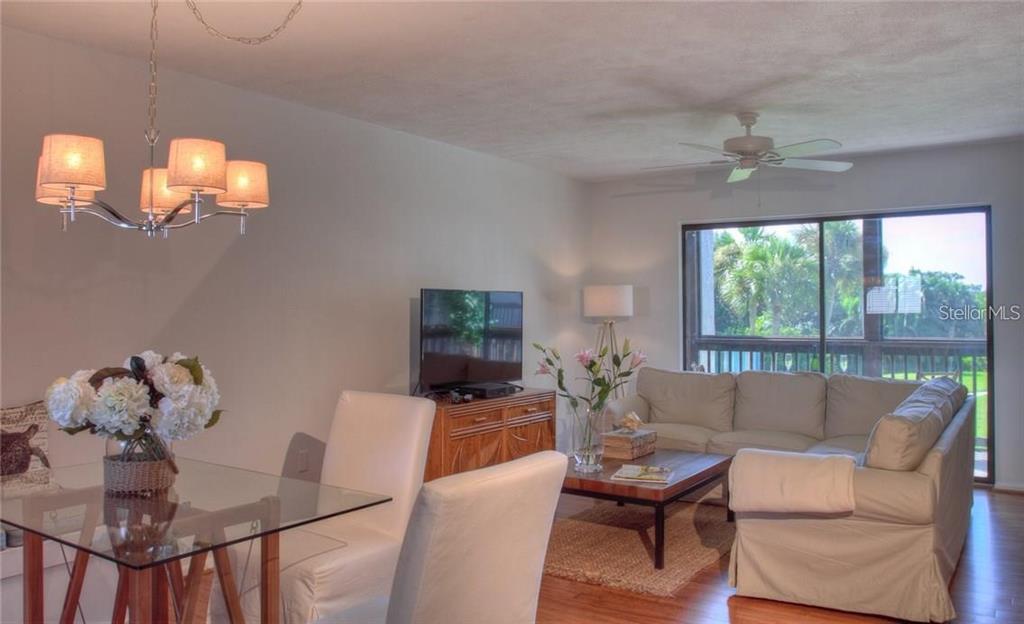 A living and dining area features a glass table, white chairs, and a beige sectional sofa — 1622 STICKNEY POINT ROAD UNIT 22-202, SARASOTA, FL