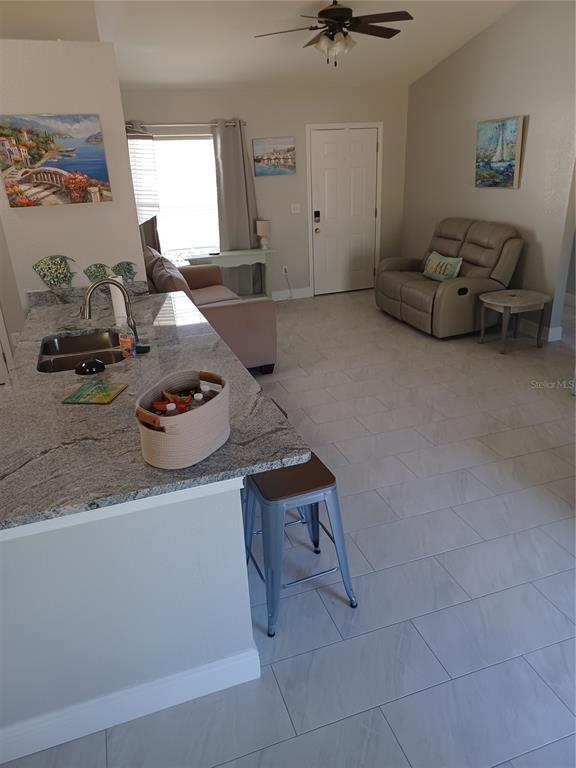 A kitchen island with a granite countertop overlooks a living area with tile flooring — 3985 SE 138TH PLACE, SUMMERFIELD, FL