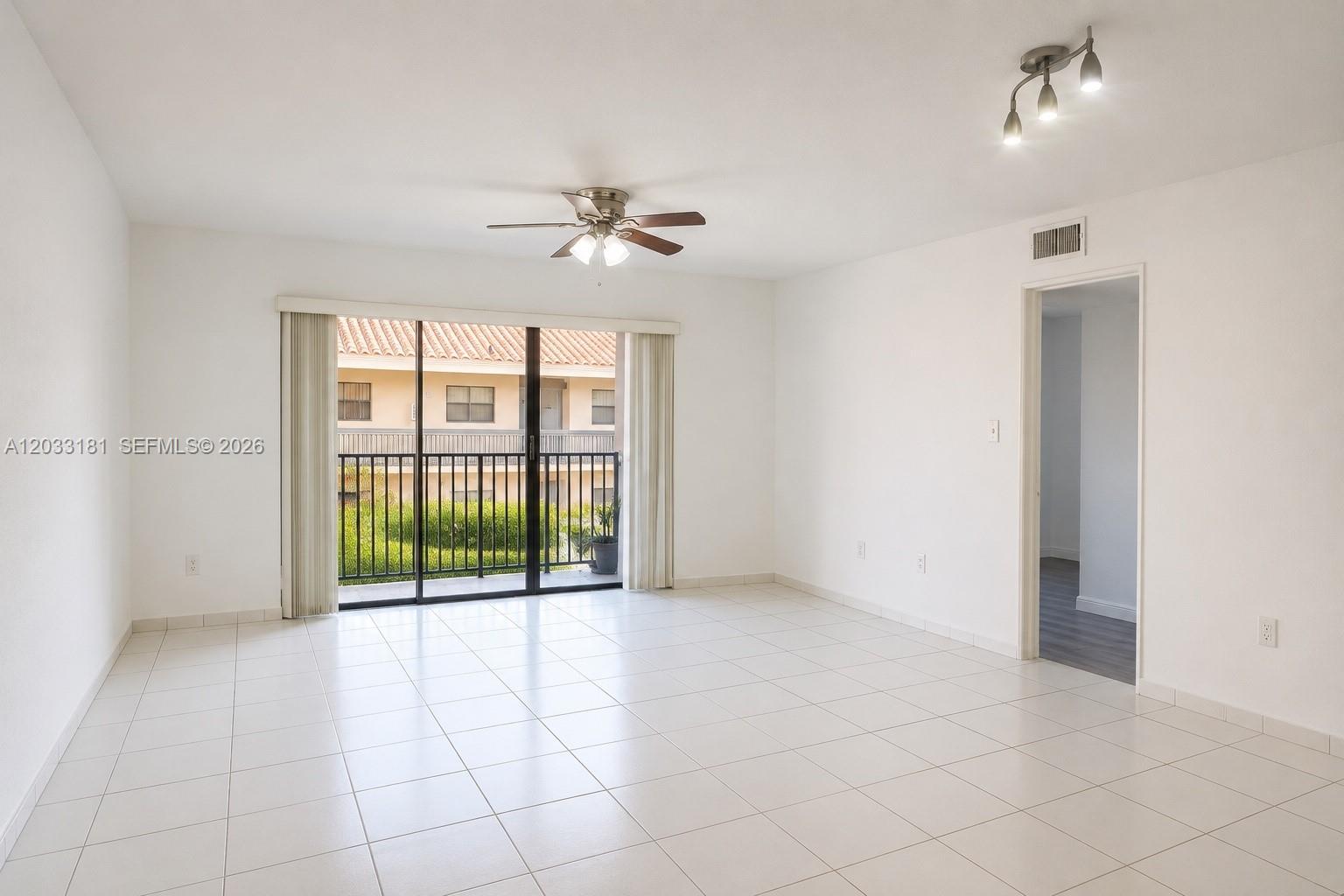 A bright living room features white tile floors, a ceiling fan, and a sliding glass door — 240 W Park Dr # 4, Miami FL 33172, MIAMI, FL