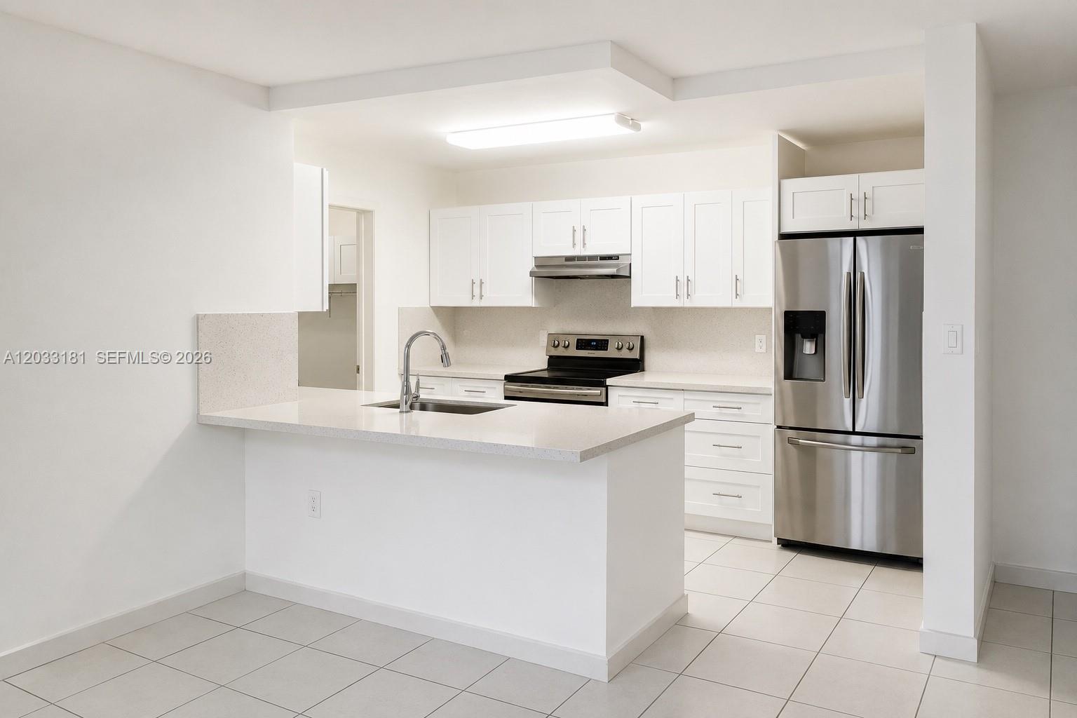 A modern kitchen features white cabinets, stainless steel appliances, and a peninsula with quartz countertops — 240 W Park Dr # 4, Miami FL 33172, MIAMI, FL