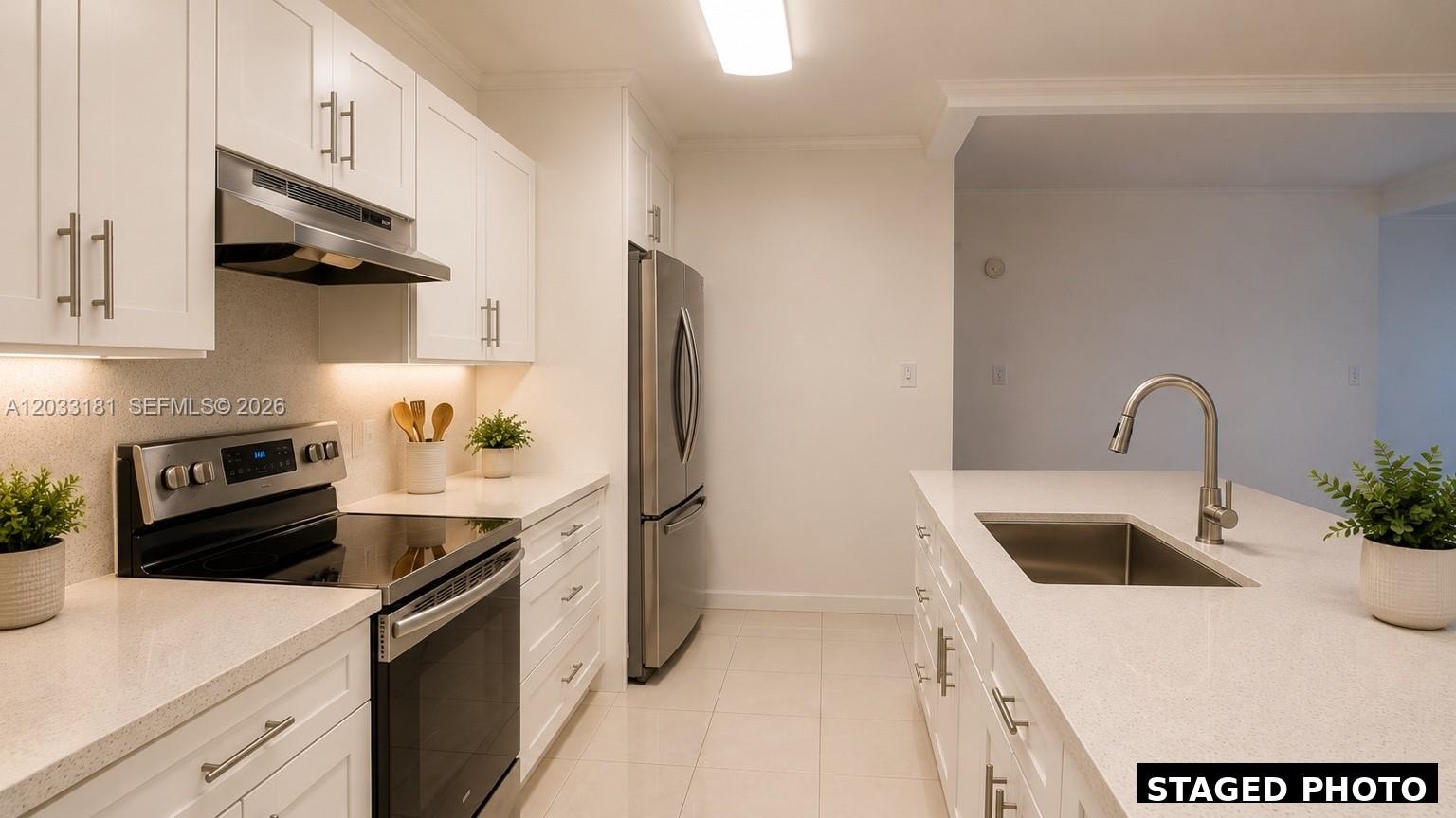 A modern kitchen features white cabinetry, stainless steel appliances, and a quartz-topped island — 240 W Park Dr # 4, Miami FL 33172, MIAMI, FL