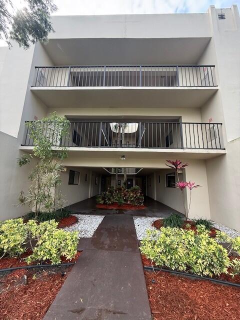 Exterior view of a multi-story apartment building with balconies and a ground-level breezeway — 5220 Las Verdes Circle # 108, Delray Beach FL 33484, DELRAY BEACH, FL