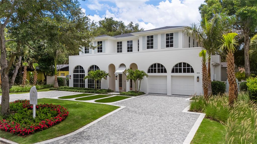 A two-story white house features arched windows, a paved driveway, and manicured landscaping — 1836 WHITEHALL DRIVE, WINTER PARK, FL