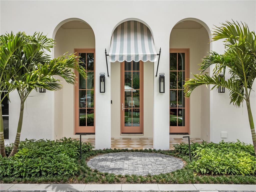 A white exterior wall features three arched doorways with peach-colored frames and a striped awning — 1836 WHITEHALL DRIVE, WINTER PARK, FL