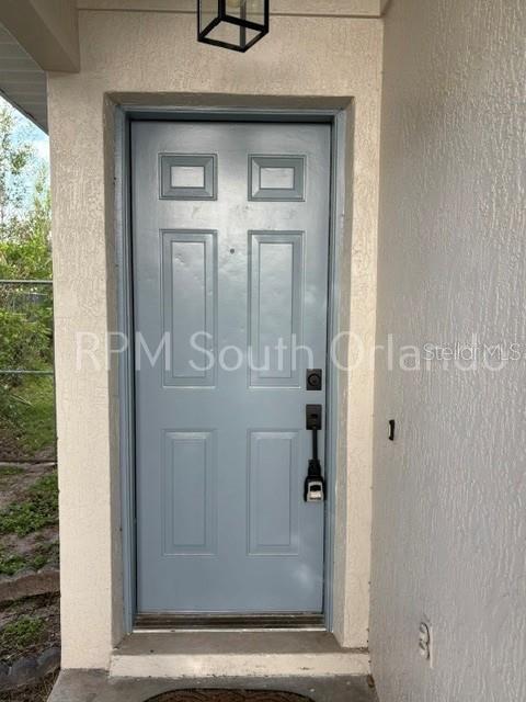 A light blue, six-panel front door with a black lockbox is set in a stucco entryway — 1930 TEABERRY COURT, ORLANDO, FL