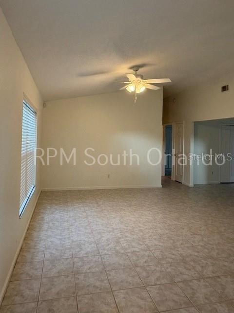 An empty room features light-colored tile flooring, a vaulted ceiling with a fan, and blinds — 1930 TEABERRY COURT, ORLANDO, FL