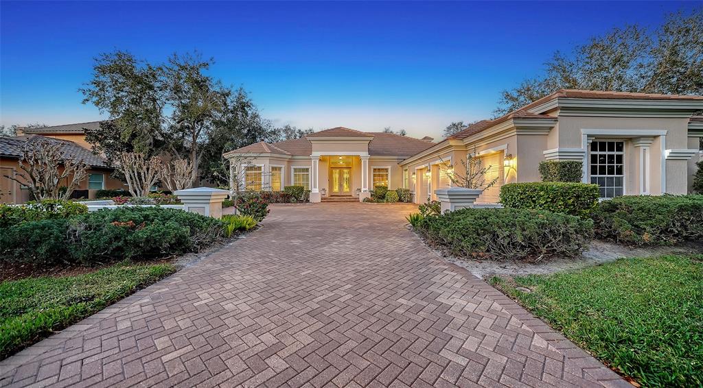 A single-story house with a brick paver driveway and a three-car garage at dusk — 480 ORISKANY COURT, OSPREY, FL