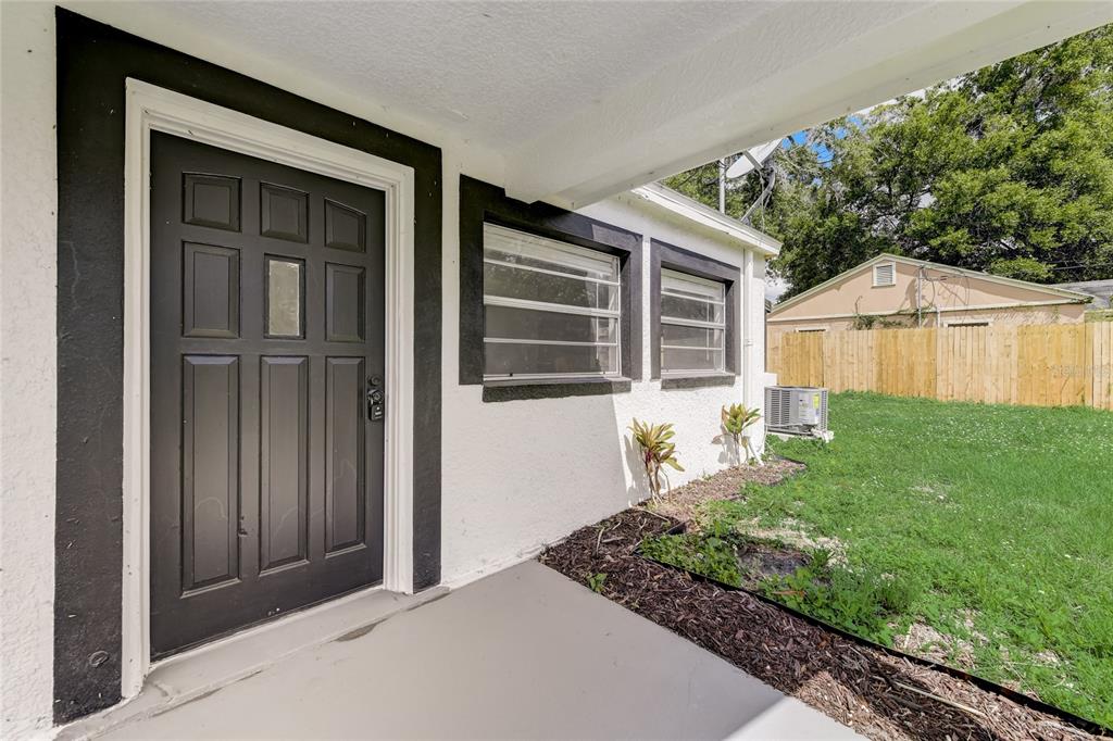 A dark front door and two windows are set into the white exterior of a house — 2600 S CRYSTAL LAKE DRIVE, ORLANDO, FL