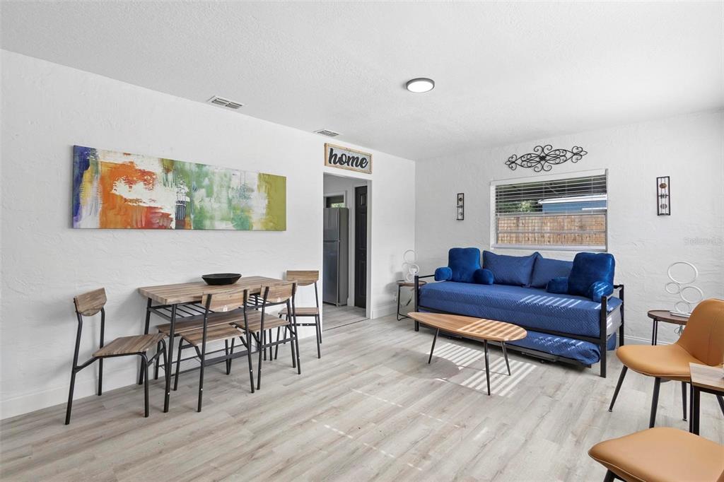 A living and dining area features white walls, light wood flooring, and blue furniture — 2600 S CRYSTAL LAKE DRIVE, ORLANDO, FL