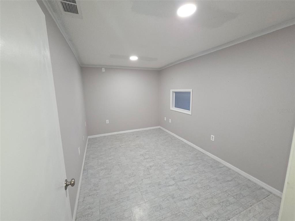 An empty room features light gray walls, a tiled floor, and a small rectangular window — 7154 CONGRESS STREET, NEW PORT RICHEY, FL