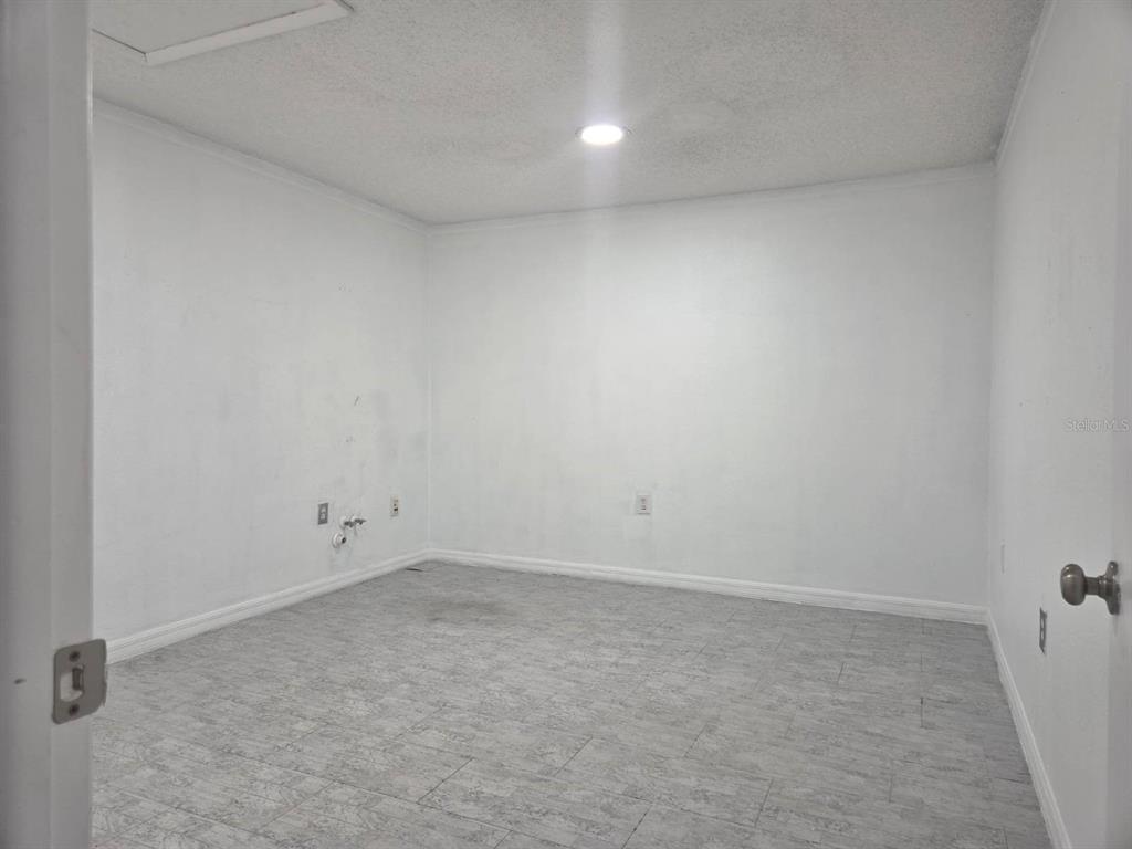 An empty room with white walls, gray tile flooring, and a ceiling light fixture — 7154 CONGRESS STREET, NEW PORT RICHEY, FL