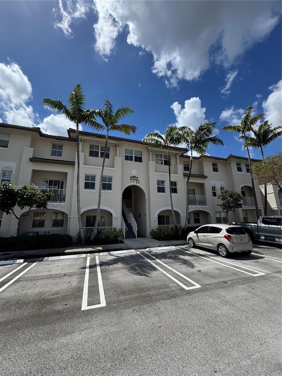 A three-story apartment building with palm trees and a parking lot in the foreground — 11601 NW 89th St # 209, Doral FL 33178, DORAL, FL