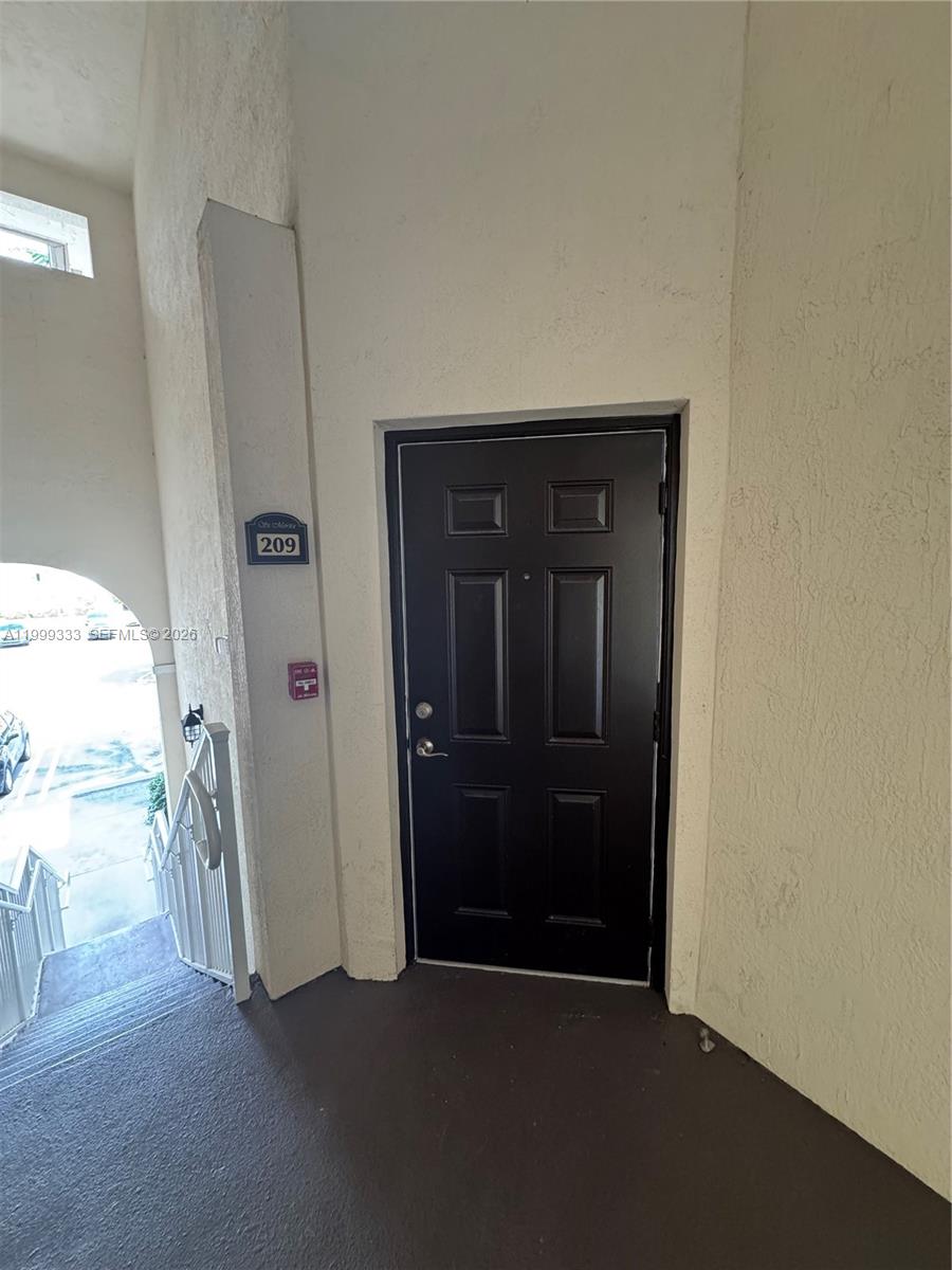 A dark-colored front door with a unit number sign is located at the top of stairs — 11601 NW 89th St # 209, Doral FL 33178, DORAL, FL