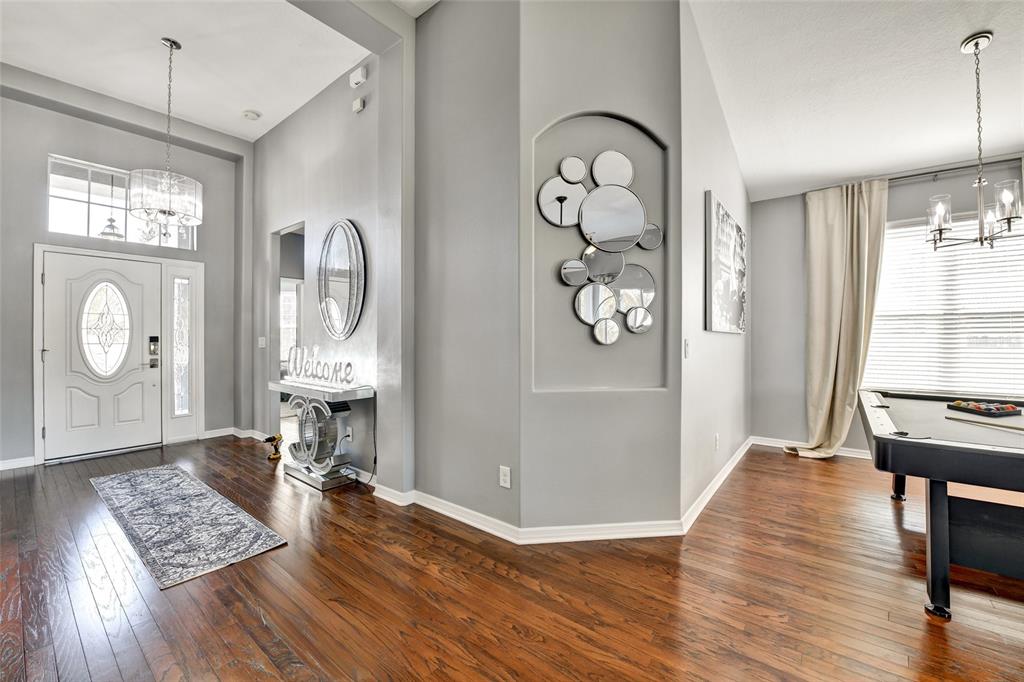 An entryway with hardwood floors, a pool table, and a decorative wall mirror display — 7514 FOREST MERE DRIVE, RIVERVIEW, FL