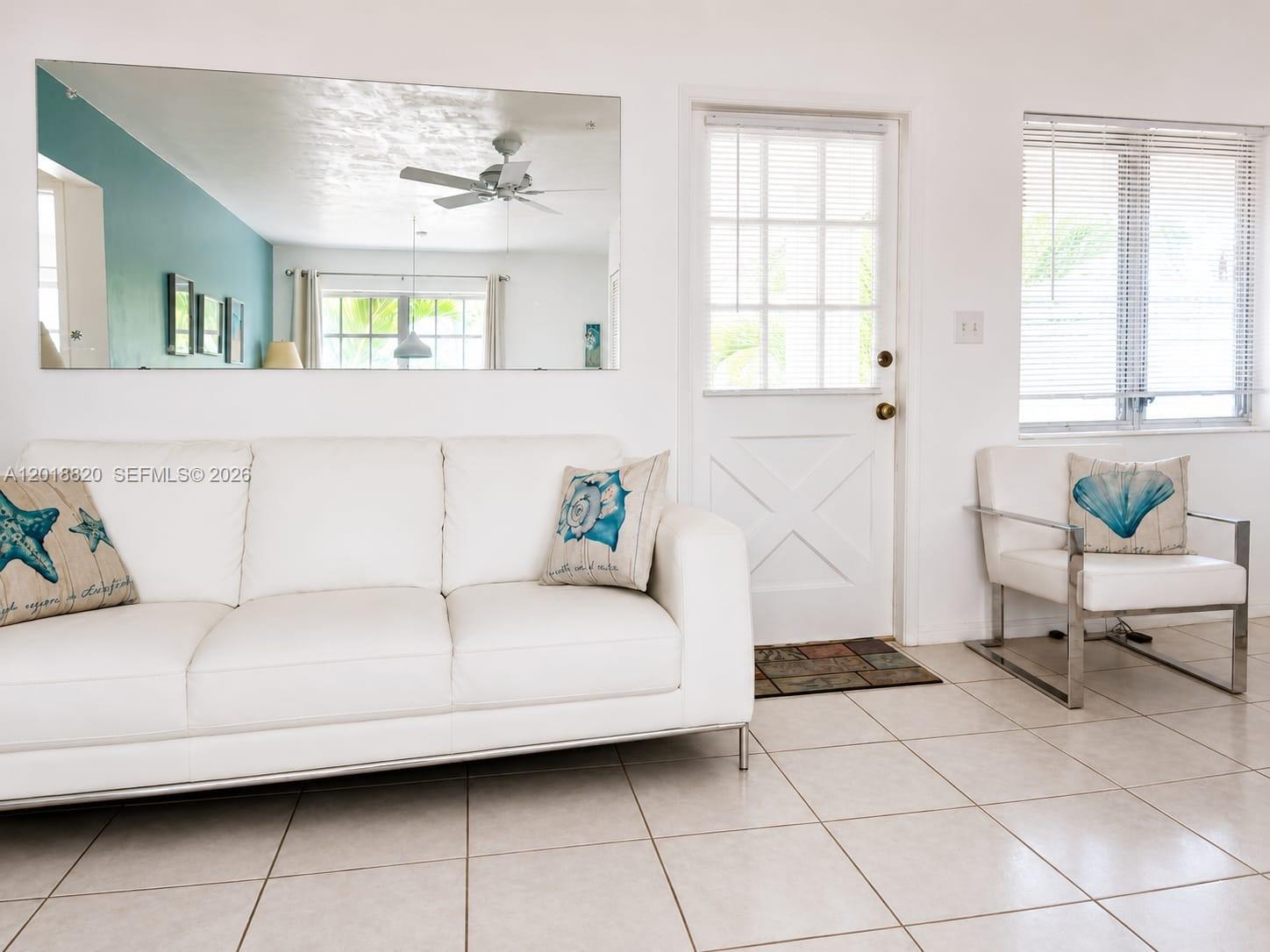 A white sofa and chair sit on tiled floors near a door and window — HOLLYWOOD, FL