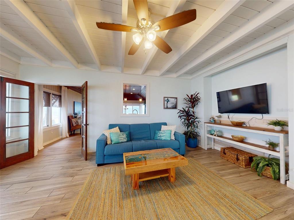 A living room features a blue sofa, wood coffee table, ceiling fan, and white beamed ceiling — 1011 Hill STREET, NEW SMYRNA BEACH, FL