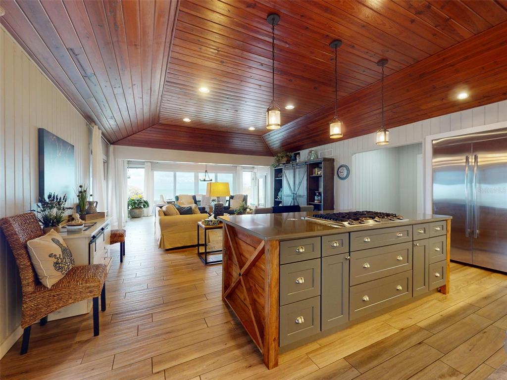A kitchen with a gray island and wood-paneled ceiling opens into a bright living area — 1011 Hill STREET, NEW SMYRNA BEACH, FL
