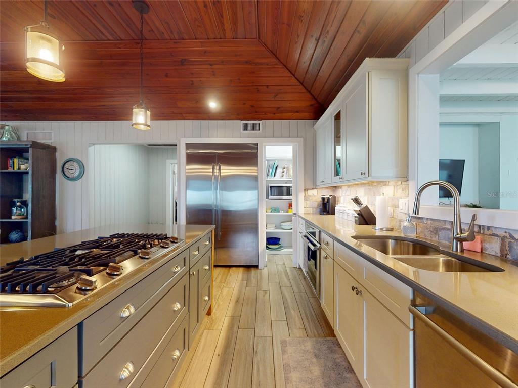 A kitchen features a wood-paneled ceiling, stainless steel appliances, a large island, and light-colored cabinetry — 1011 Hill STREET, NEW SMYRNA BEACH, FL