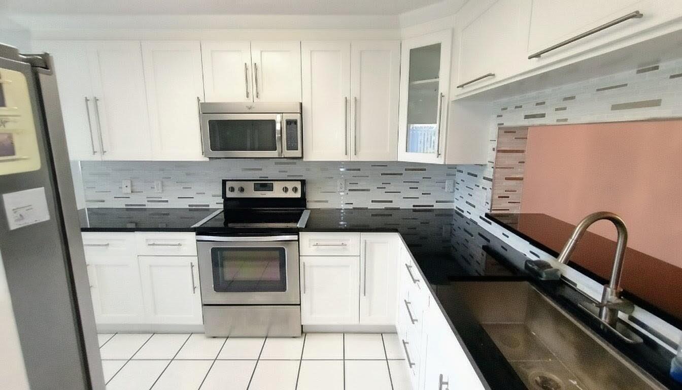 A kitchen with white cabinets, black countertops, stainless steel appliances, and a tiled backsplash — 4735 E Lucerne Lakes Boulevard E # 413, Lake Worth FL 33467, LAKE WORTH, FL