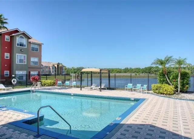 A swimming pool with a covered patio area sits in front of a multi-story apartment building — 2210 GRAND CAYMAN COURT UNIT 1737, KISSIMMEE, FL