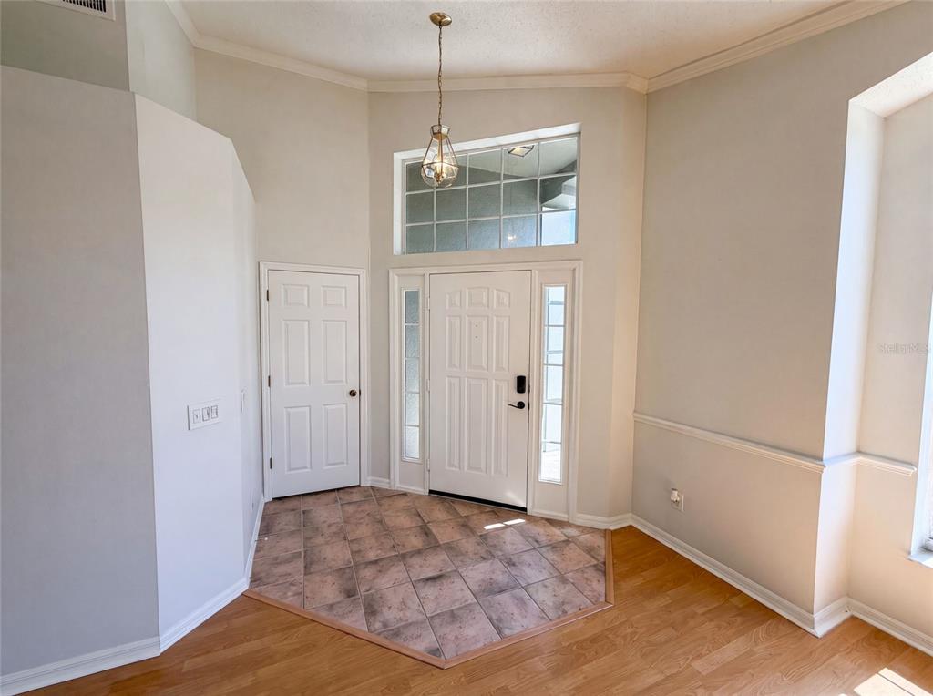 An entryway features a tiled floor, a white front door with sidelights, and a pendant light — 701 MAGNOLIA CREEK CIRCLE, ORLANDO, FL
