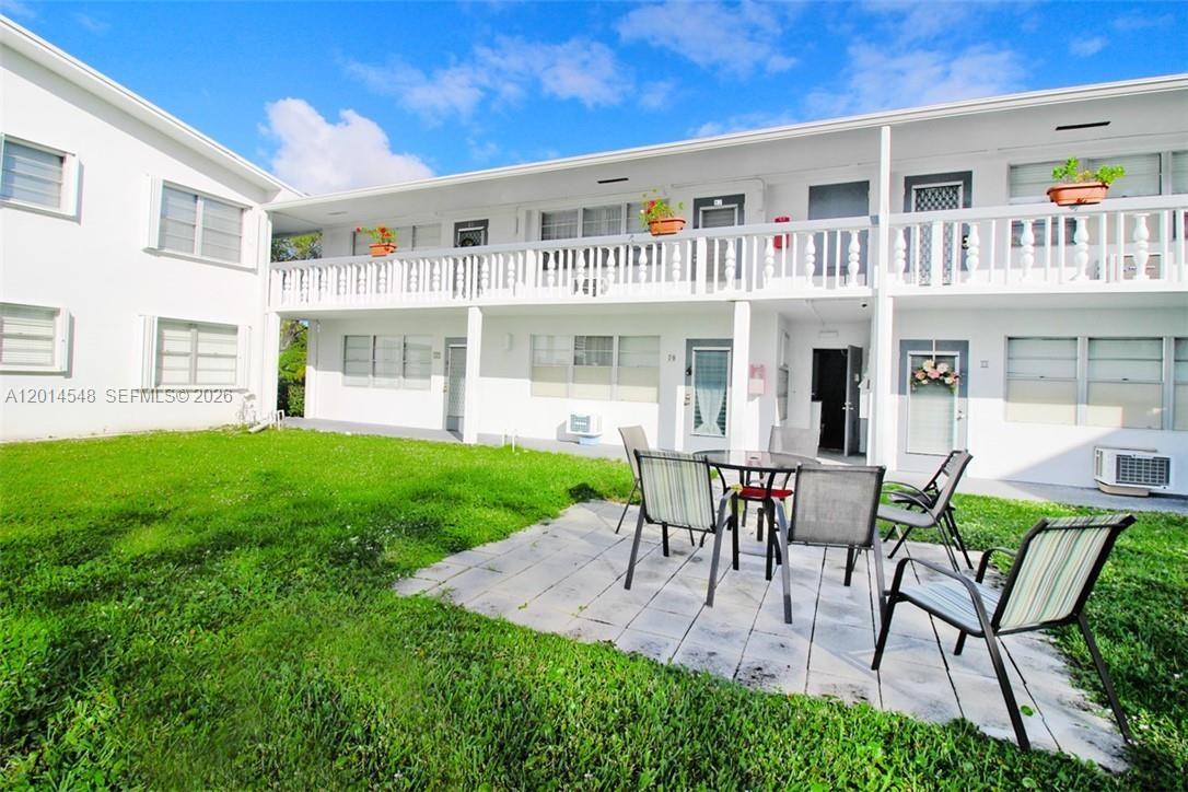 A two-story white apartment building features a ground-level patio with outdoor furniture and grass — 70 Prescott D # 70, Deerfield Beach FL 33442, DEERFIELD BEACH, FL
